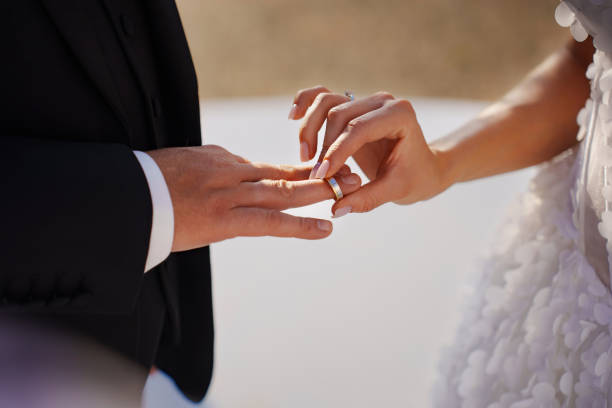 istock without faces. The bride puts the wedding ring on the groom's finger. 2189156346