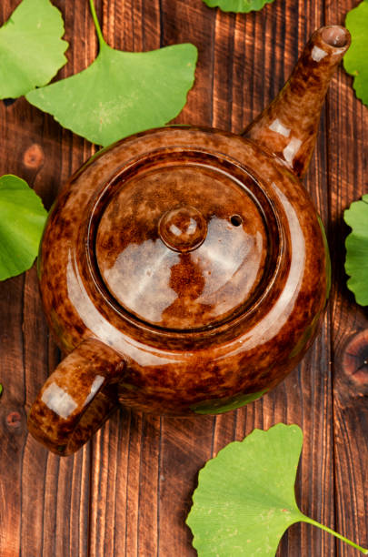 Teapot with Ginkgo biloba tea on a wooden table. Extract or tee from the ginkgo with leaves. Flat lay.