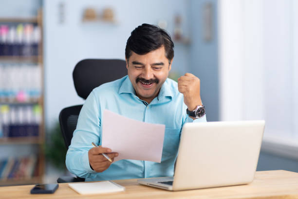 istock Happy business professional analyzing documents while sitting at desk in office stock photo 2189156655
