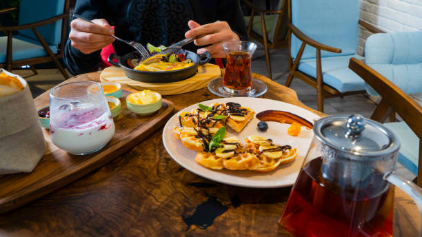 istock Brunch spread: waffles, tea, and colorful dishes on a wooden table 2189157417