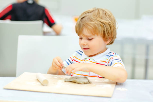 Little blond boy modeling with clay at master class art in a museum, indoors. Creative leisure for kids in kindergarden and at home, indoors.