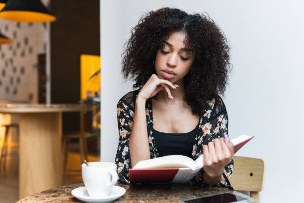 istock Ethnic woman reading book at cafe table 2189159803