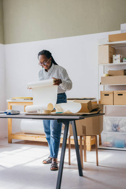 istock Young Woman Working in a Bright Creative Studio with Cardboard Boxes 2189159980