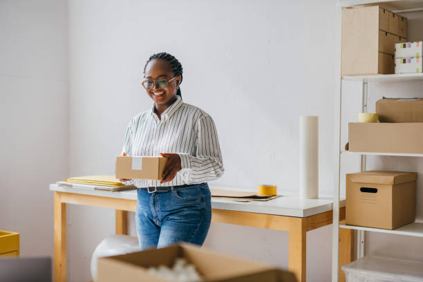 istock Smiling Female Entrepreneur Holding Package in Small Business Workspace 2189160010