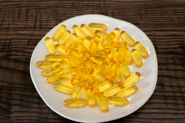 istock Yellow capsules arranged on a white plate over a wooden background 2189160118