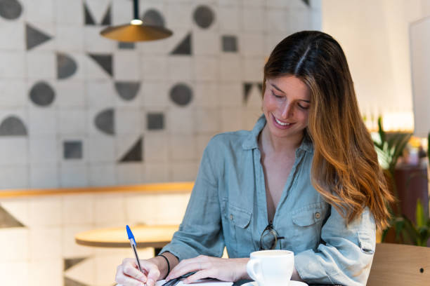 istock Dreamy woman with notebook and tea in cafe 2189160434