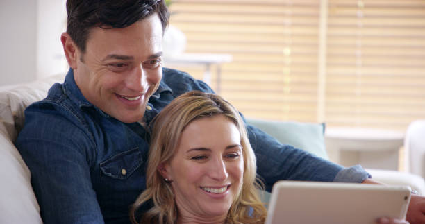 istock Smile, couple and tablet on sofa in home with video streaming, series and technology from meme. Internet, watching and love of happy people with app, online and fun together on weekend with care 2189163779