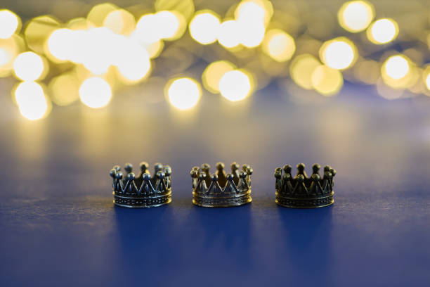 istock three shiny crowns and a lights on blue background. Epiphany and three kings day holiday celebration. 6 January 2189164349