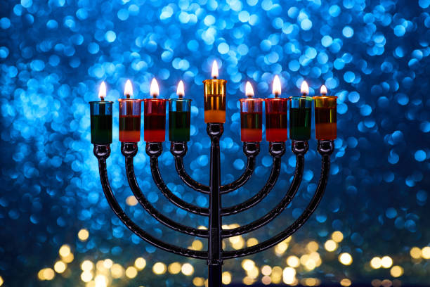 istock Hanukkah Menorah with burning candles on dark background with bokeh lights. 2189166305