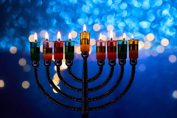 istock Hanukkah Menorah with burning candles on dark background with bokeh lights. 2189166422