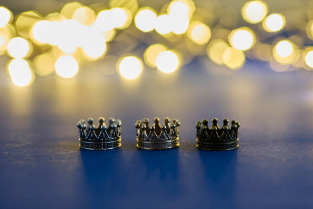 istock three shiny crowns and a lights on blue background. Epiphany and three kings day holiday celebration. 6 January 2189167370