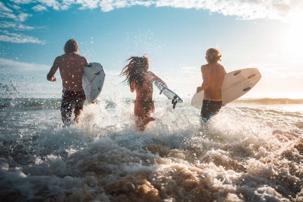 Joyful Caucasian Friends Surfing at Sunrise