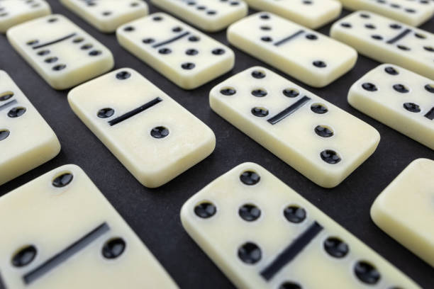 Flat lay composition of chess pieces and dominoes on dark table.