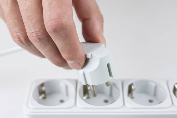 istock Close-up of woman's hand inserting electric plug into socket. Connecting electrical devices 2189173350