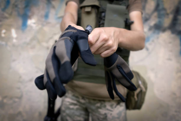 A soldier puts tactical gloves on her hands, a woman in military uniform is preparing for her working day at the front line, closeup view.