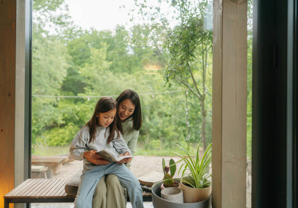 Mother and daughter reading together by the window