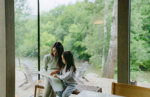 istock Mother and daughter reading together by the window 2189177020