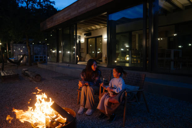 Photo of a cheerful mother and daughter on a  pleasant spring evening, bonding by the fire