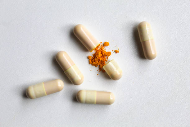 istock Opened capsule with yellow turmeric powder filling inside. Isolated on white background, flat lay or top view 2189179887