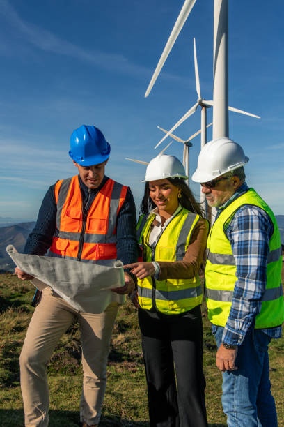 Engineers examining blueprint in front of wind turbines