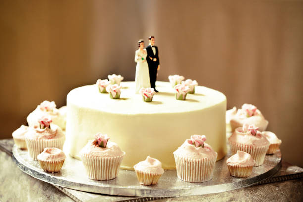 istock A wedding cake with cupcakes around it and a couple topper on it. 2189183629
