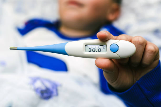 istock Child shows electronic thermometer with high temperature. Child lying in bed, close-up. 2189185180