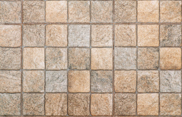 Beige square ceramic tiles in close-up, forming a seamless pattern ideal for interior design backgrounds and textures