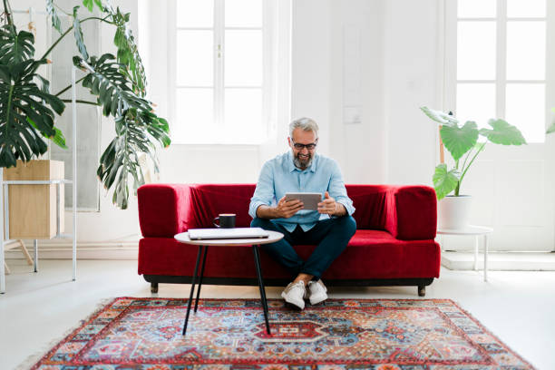 istock Smiling senior man using digital tablet, drinking coffee and working at home 2189187638