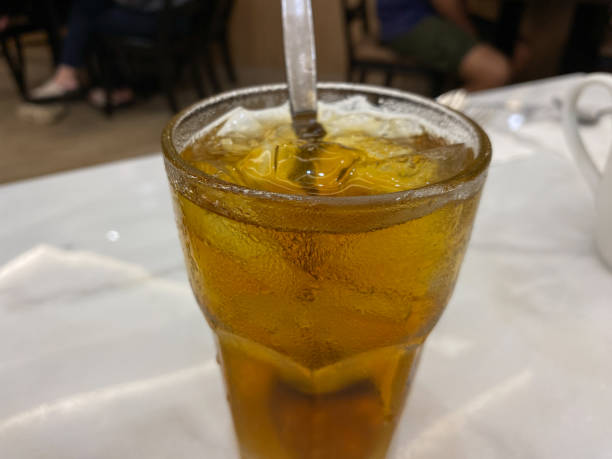 Stock photo showing close-up view of citrus orange mock cocktail with ice cubes and lime slice in drinking glass covered in condensation.