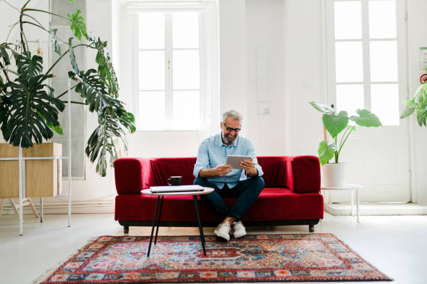 istock Smiling senior man using digital tablet, drinking coffee and working at home 2189187746