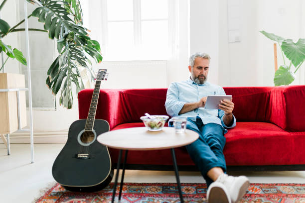 istock Senior man using digital tablet and eating fresh salad at home office 2189191006