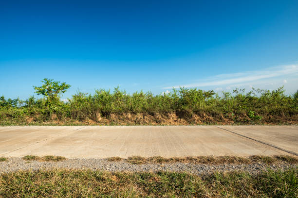Side view of concrete road and meadow with blue sky.