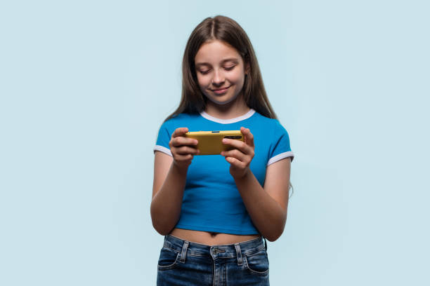 A young girl holding a yellow smartphone, engaged and focused, possibly gaming or browsing.
