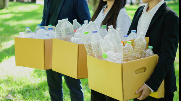 Employees collaborate on recycling campaign, sorting plastic bottles and cardboard boxes driving eco-friendly initiatives and promoting sustainability in the workplace.