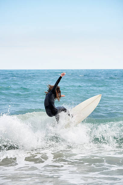 istock Surfboarder with long hair riding a wave 2189200020