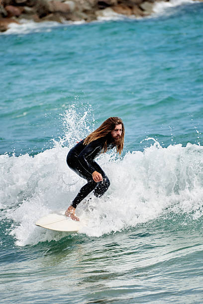 concentrated long-haired man riding waves on surfboard