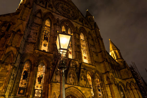 Tranquil, night scene of a vintage wrought iron street lantern seen lit against a majestic cathedral in York, England. stock photo
