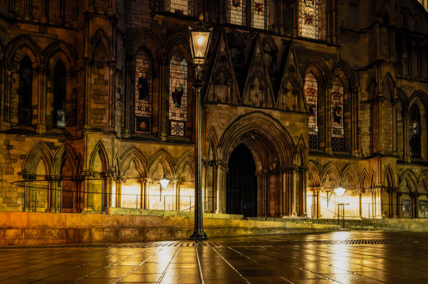 Tranquil, night scene of a vintage wrought iron street lantern seen lit against a majestic cathedral in York, England. stock photo