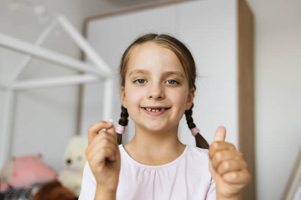 istock Joyful young girl holding her fallen tooth at home 2189209836