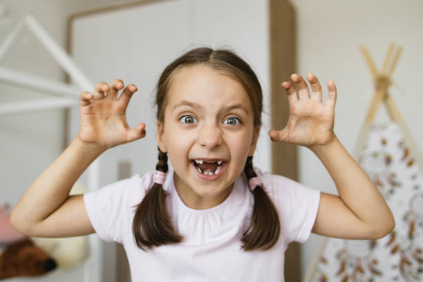 istock Playful young girl with missing teeth making scary face at home 2189209896