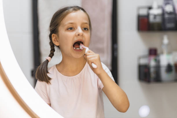 istock Little girl with missing teeth brushing teeth in bright bathroom 2189209965