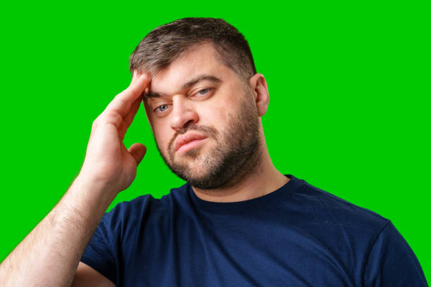 istock A man with closed eyes holds his head in a thoughtful pose against a bright green backdrop 2189217471