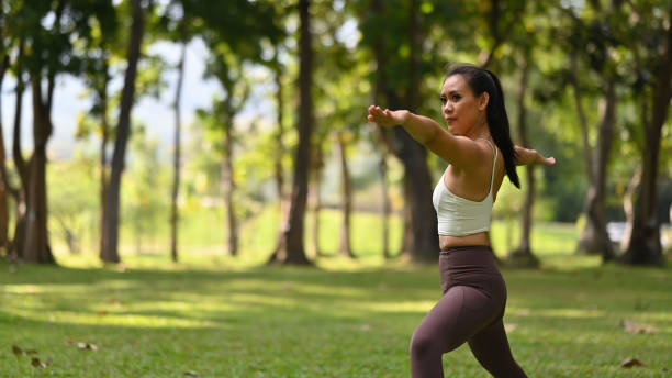 istock A woman performs Warrior II pose outdoors, arms extended parallel to the ground, front knee bent, and gaze over the front hand, exuding focus and balance amidst nature 2189219690