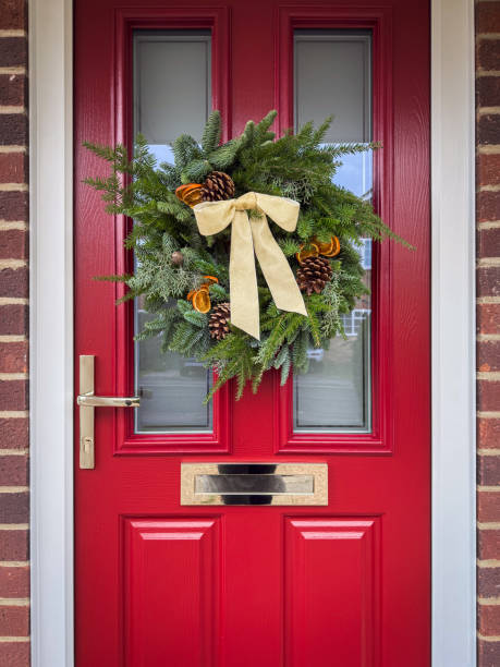Homemade Christmas wreath hanging on front red door of an English home.