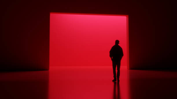 Silhouette of a Person Standing in Front of a Red-lit Portal stock photo