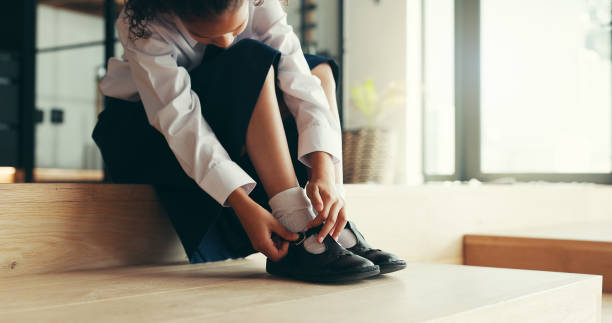 Hands, child and tie shoes for school as morning routine,  getting ready in home or preparation for education. Feet, uniform and girl student with start to day for learning, dressing or footwear