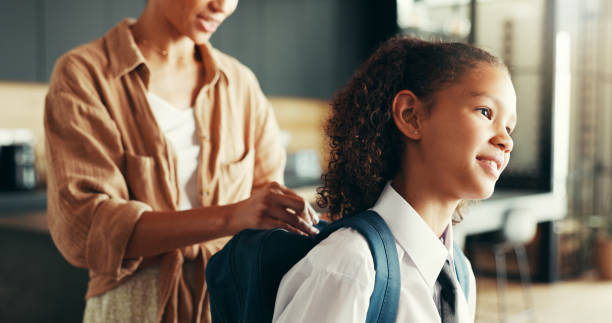 istock Mom, girl and happy with backpack in home for preparing or ready for elementary education. Apartment, people and parent with kid in uniform for first day at school with smile, pride and child growth 2189228361
