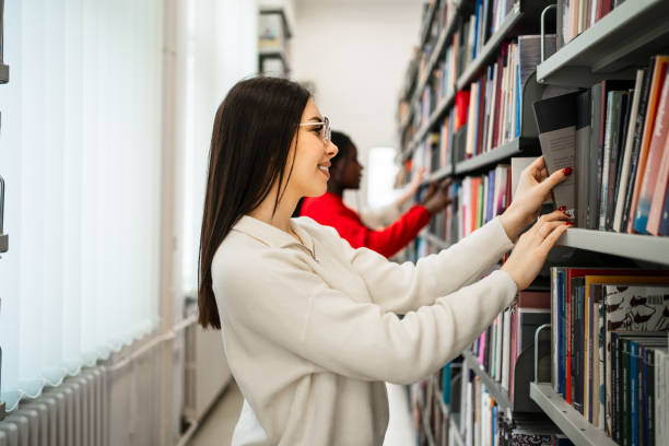 istock Young female student choosing a book in the library 2189229239