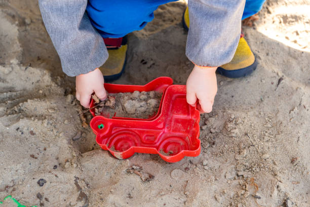 Cutout of a toddler playing with toys in a sandbox
