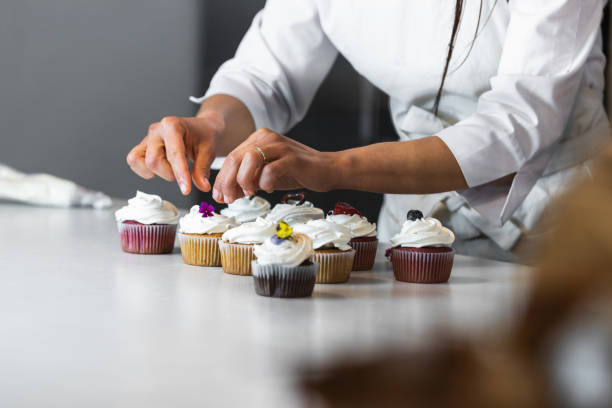 istock Crop woman decorating cupcakes on table in kitchen 2189239357